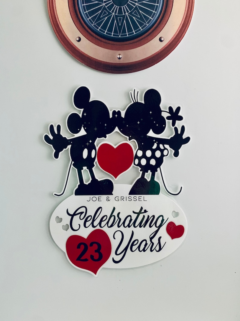 Może przedstawiać: Czarna sylwetka Myszki Miki i Minnie Mouse całujących się z czerwonym sercem w środku. Poniżej znajduje się owal z tekstem "JOE & GRISSEL Celebrating 23 Years" z czerwonym sercem po obu stronach tekstu.