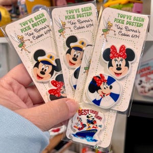 May include: A collection of Disney-themed magnets featuring Mickey and Minnie Mouse, and a cruise ship design. Each magnet is packaged on a card with the text "YOU'VE BEEN PIXIE DUSTED! The Sierra's Cabin 6194" and a Tinkerbell graphic. The "BEST CRUISE EVER!" magnet is also included.