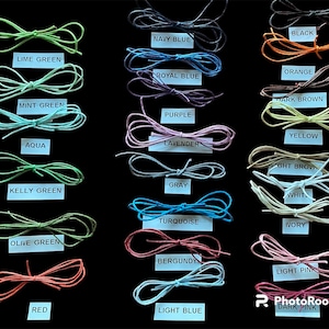 May include: A collection of shoelaces in various colors, including lime green, navy blue, and red, are displayed against a black background. Each pair is neatly tied into a bow, with labels indicating the color name. Colors include black, orange, and dark pink.
