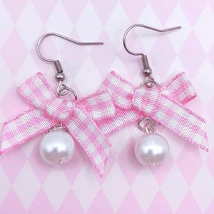 May include: Pink and white gingham ribbon bow earrings with a pearl accent.