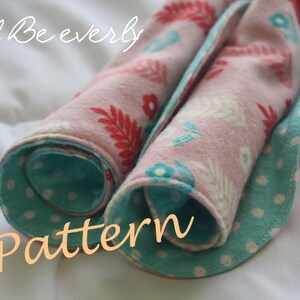 May include: Two rolled up fabric squares with a floral pattern on one side and a teal polka dot pattern on the other side. The fabric is pink with red and white floral designs. The teal fabric has white polka dots. The text "E Pattern" is written in orange on a white background.