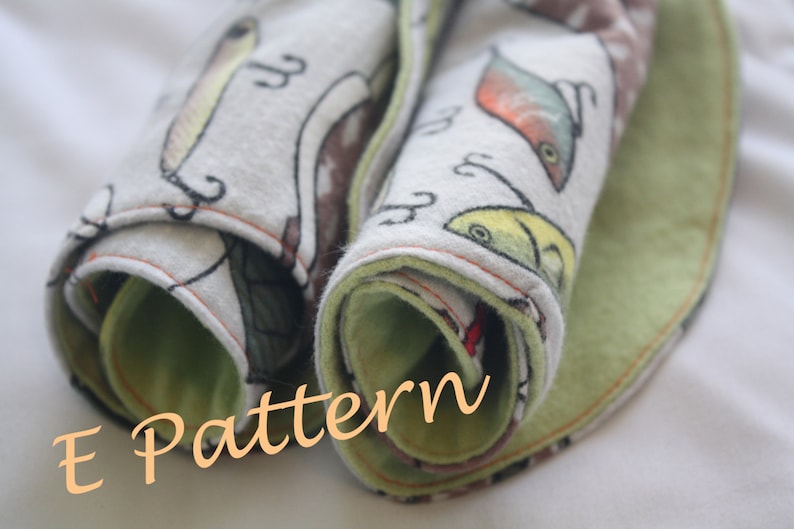 May include: A rolled up fabric with a green and white fish print. The fabric is folded over and has a green border. The text "E Pattern" is written in orange on the fabric.