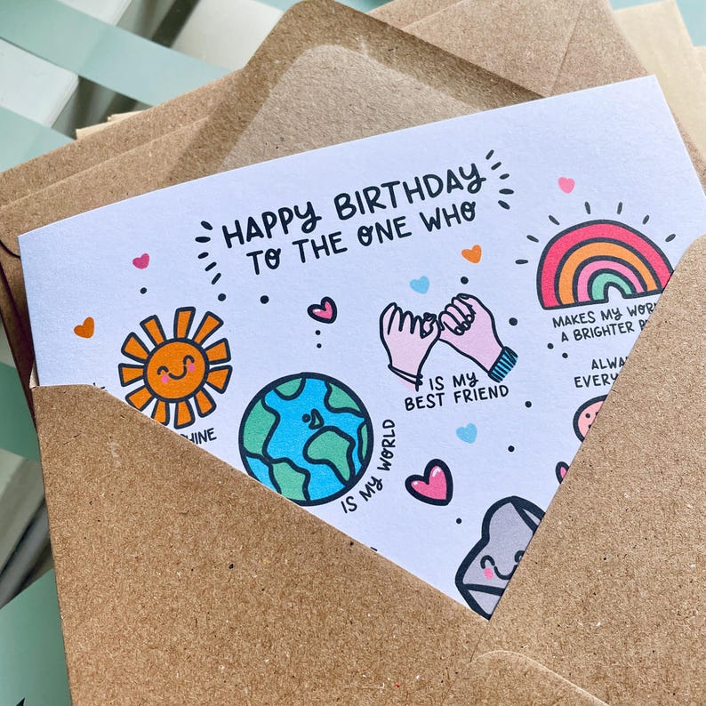 May include: A white greeting card inside a brown kraft paper envelope. The card features colorful illustrations including a smiling sun, a globe, pinky-promising hands, and a rainbow, with text reading Happy Birthday to the one who is my best friend.