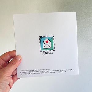 May include: Square white card with a stamp-like illustration of an envelope with a heart and moon. The word "LUNELLA" is below the stamp. Text at the bottom reads "ART BY LYNDSAY MOON &copy; 2025 ALL RIGHTS RESERVED..." and a website address.
