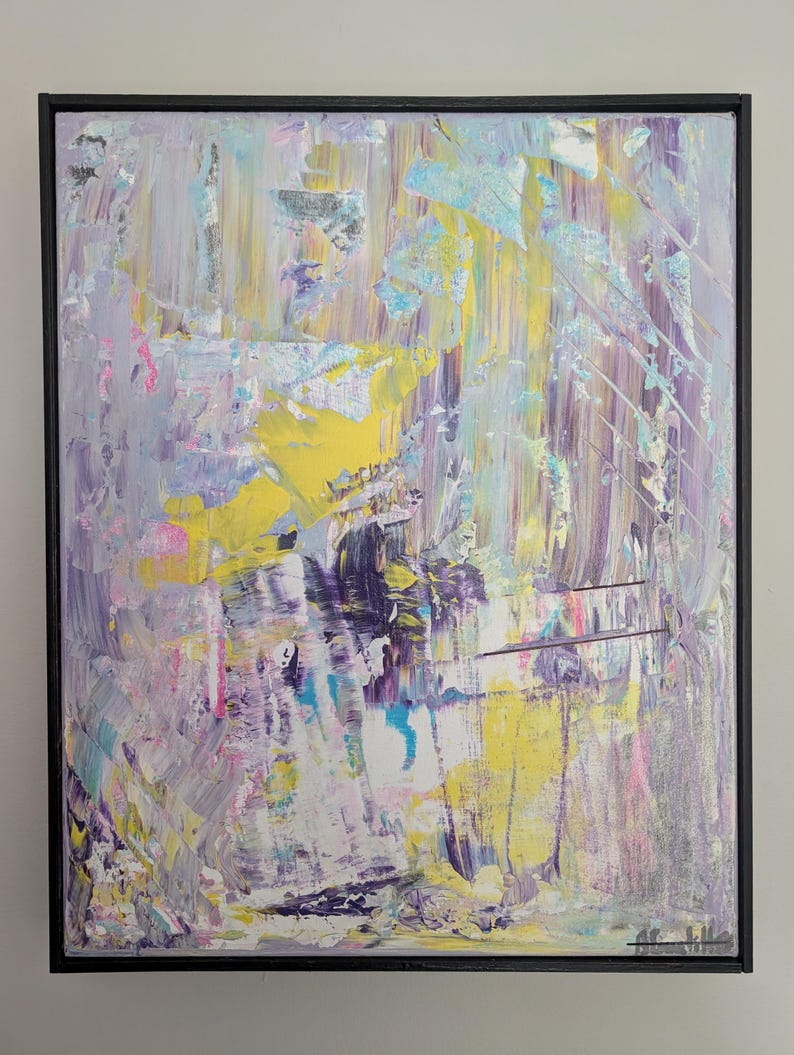 May include: Abstract painting with a black frame. The artwork features a textured surface with a palette of colors including yellow, purple, blue, and pink. The brushstrokes create a dynamic and expressive composition.