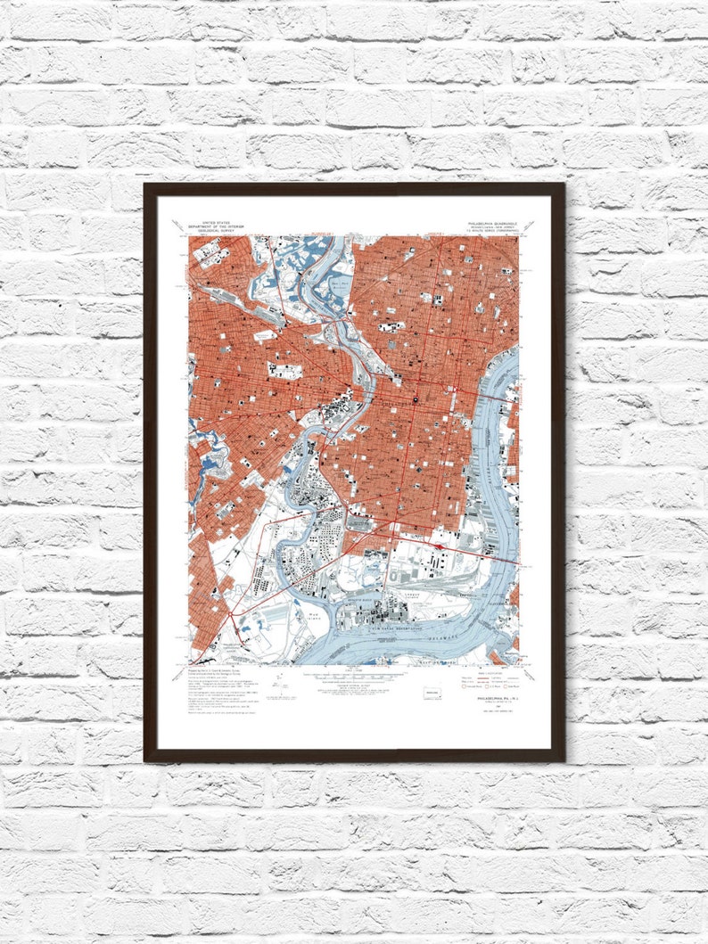 May include: A vintage map of Milwaukee, Wisconsin, showing the city's streets, rivers, and landmarks. The map is printed in shades of blue, red, and black on a white background. The map is framed in a brown frame.