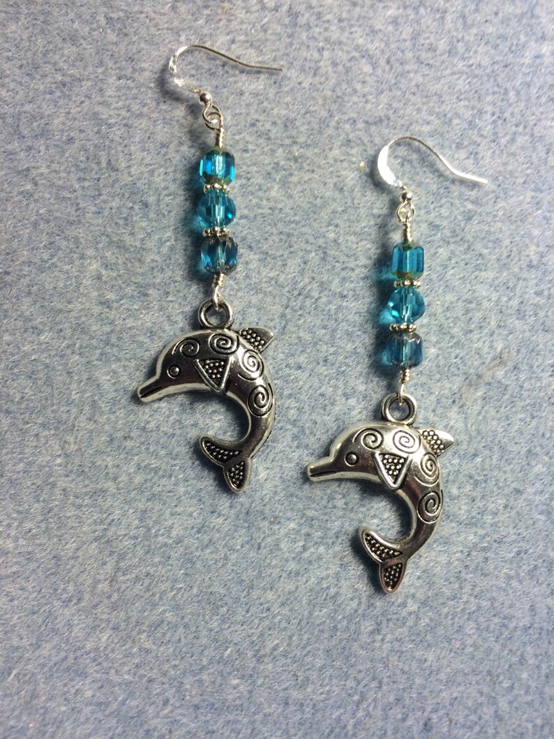 Silver dolphin charm dangle earrings adorned with turquoise Czech glass beads.