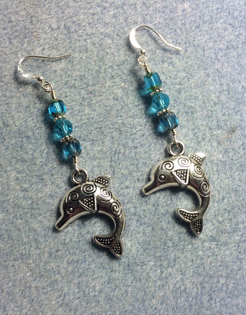 Silver dolphin charm dangle earrings adorned with turquoise Czech glass beads.