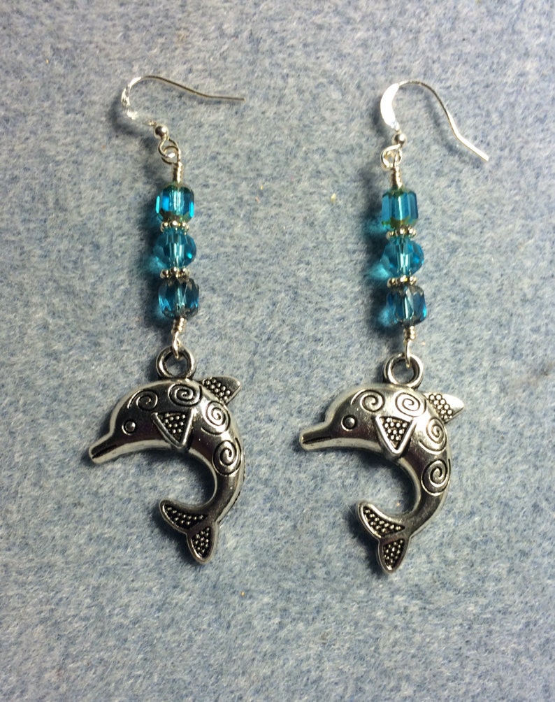 Silver dolphin charm dangle earrings adorned with turquoise Czech glass beads.
