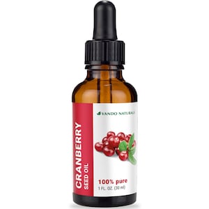 Könnte beinhalten: Eine braune Glasflasche mit Cranberry-Samenöl und einer schwarzen Pipette. Das Etikett trägt den Text "CRANBERRY SEED OIL" und "100% pure 1 FL. OZ. (30 ml)". Eine Grafik von Cranberries und Blättern befindet sich ebenfalls auf dem Etikett. Der Markenname "VANDO NATURALS" ist ebenfalls sichtbar.