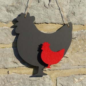 May include: Black silhouette of a chicken with a red felt chick inside. The chicken is hanging from a string.