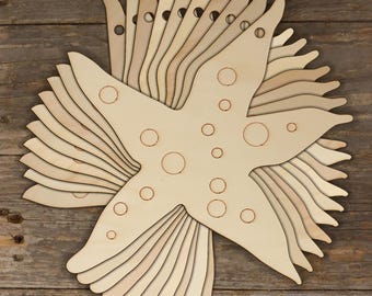 Pode incluir: Uma pilha de 12 enfeites de estrela do mar de madeira inacabados com um design pontilhado. As estrelas do mar medem aproximadamente 12,5 cm de largura e têm um furo no topo para pendurar.