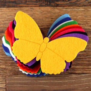 May include: A yellow felt butterfly cutout with a layered stack of felt fabric in various colors behind it. The colors include blue, white, green, red, black, purple, and orange.