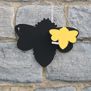 May include: Black chalkboard shaped like a bee with a smaller yellow bee cutout on the right side. A piece of chalk is included.