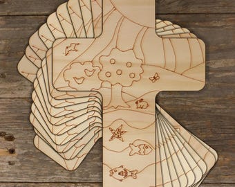 May include: A stack of unfinished wooden cross-shaped ornaments with a nature-themed design. The design features a tree, birds, a butterfly, a rabbit, a starfish, and fish. The ornaments are ready to be painted or stained.