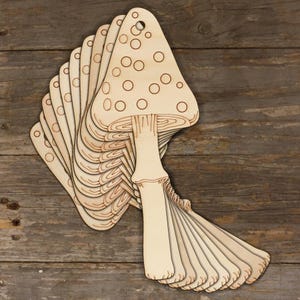 May include: A stack of wooden mushroom-shaped ornaments with a white background and brown dots. The ornaments are layered on top of each other, creating a 3D effect.