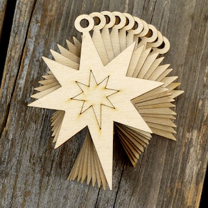 May include: A stack of unfinished wooden star ornaments with a small hole at the top for hanging. The stars have a simple, classic design with a smaller star cut out in the centre.
