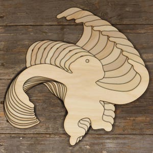 Puede incluir: Una pila de formas de mono de madera sin terminar, listas para ser trabajadas y pintadas. El mono está en una pose juguetona con los brazos levantados y la cola enroscada.