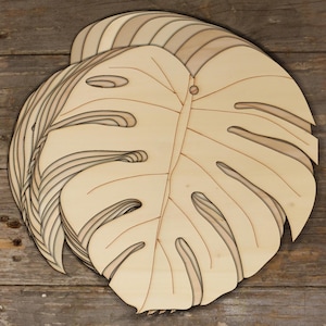 May include: A wooden cutout of a monstera leaf, with intricate details and a natural wood finish.