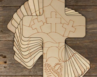 May include: A stack of 12 unfinished wooden crosses with a stained glass design featuring three crosses, a tomb, and a palm branch. The crosses are ready to be painted or decorated.