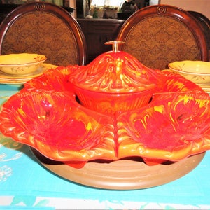 May include: A red and orange ceramic serving dish with four individual bowls and a lidded bowl in the center. The dish is decorated with a floral design.