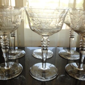 May include: Set of six clear glass champagne coupes with a cut glass design. The coupes have a wide bowl and a tall, slender stem.