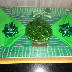 May include: A set of green placemats with matching napkins and a green glass coaster. The placemats and napkins have a silver trim and the coaster is made of crushed glass. The set is packaged in a box with a gold trim.