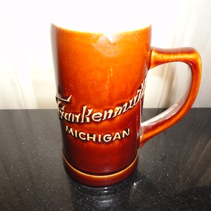 May include: A set of three ceramic mugs with a speckled, matte finish. The mugs are in shades of cream, light gray, and dark gray. Each mug has a simple, minimalist design and a rounded handle.