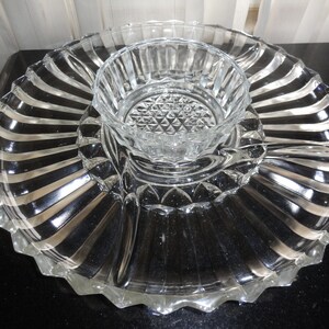 May include: A clear glass serving dish with a central bowl and four smaller compartments. The dish has a fluted edge and a striped design.