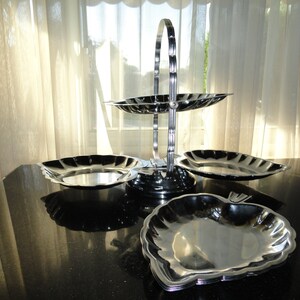 May include: A three-tiered silver serving stand with a handle. The stand has three heart-shaped plates.