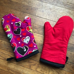 May include: Two oven mitts, one red and one purple with a heart and star wars character pattern.
