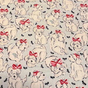 May include: Light blue fabric with a repeating pattern of white cartoon dogs wearing pink bows. Black bow accents are scattered throughout the design. The dogs are in various poses, creating a playful and whimsical aesthetic.