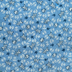 May include: Light blue fabric with a repeating pattern of white anchors, teddy bears, and sailboats. The anchors and teddy bears are white, while the sailboats are white with blue accents. The fabric has a nautical theme.
