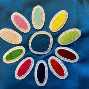 May include: A blue background with a white outline of a flower with 12 petals. Each petal is a different color, including pink, yellow, green, red, and blue. The center of the flower is blue.