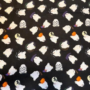 May include: Black fabric with a repeating pattern of white ghosts, orange pumpkins, and black cats on a full moon. Some ghosts have spider web designs. The word "boooooooo" is also printed on the fabric.