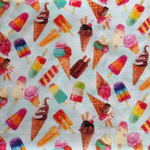 Puede incluir: Una tela azul claro con un patrón repetido de conos de helado y polos. Los conos presentan helado de chocolate, vainilla y fresa. Los polos son de varios colores, incluyendo rojo, naranja, amarillo, verde y morado.