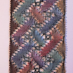 May include: A handmade bookmark with a colourful, intricate woven design. The bookmark features a repeating pattern of rainbow hues, including red, blue, and yellow, framed by a black border and finished with a black tassel.