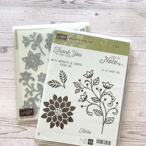 May include: Two Stampin' Up! clear stamp sets labeled Flourishing Phrases. The front set features floral designs, leaves, and text including Thank You, Just a Note, and Hello. The back set contains metal dies in matching floral and leaf shapes.