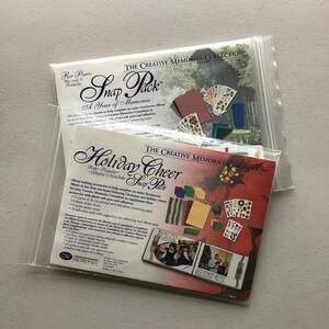 May include: Two packages of Creative Memories Snap Packs, one for a year of memories and one for holiday cheer. Each package includes a variety of paper, stickers, and embellishments for scrapbooking.