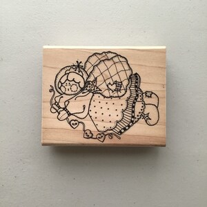 May include: A wooden stamp with a black and white illustration of a whimsical, patchwork-style figure with hearts and a star.