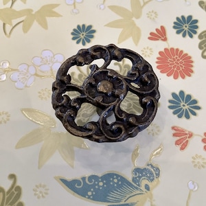 May include: A bronze-colored, ornate, decorative cabinet knob with a floral design.