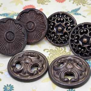May include: Six antique-style metal buttons with intricate designs. The buttons are round and have a dark brown finish. Some buttons feature floral patterns, while others have swirling designs.