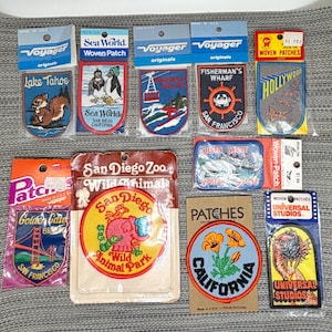 May include: A collection of ten souvenir woven patches in original packaging, featuring various California landmarks and attractions including Lake Tahoe, Sea World, Fisherman's Wharf, Hollywood, Golden Gate Bridge, San Diego Zoo, and Universal Studios.