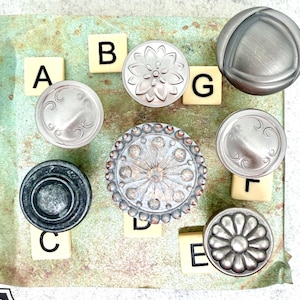 Może przedstawiać: Zestaw trzech ceramicznych kubk&oacute;w z nakrapianym, matowym wykończeniem. Kubki są w odcieniach kremowym, jasnoszarym i ciemnoszarym. Każdy kubek ma prosty, minimalistyczny design, idealny do kawy lub herbaty.