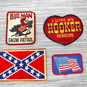 May include: Four embroidered patches: a rectangular Bud Man Snow Patrol patch, a heart-shaped patch reading I LOVE MY HOOKER HEADERS, a rectangular patch with a red field and blue saltire with white stars, and a rectangular American flag patch.