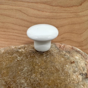 May include: A white ceramic mug with a black handle and the text "But First, Coffee" in a handwritten style. The mug is on a white surface. The mug is 4 inches tall.