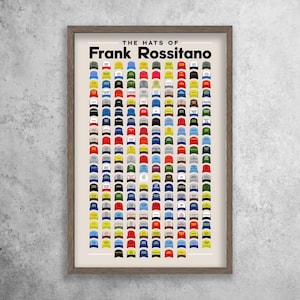 Puede incluir: Una impresión enmarcada con el título "The Hats of Frank Rossitano". La impresión presenta una cuadrícula de 100 sombreros coloridos, principalmente gorras de béisbol, con varios diseños y logotipos.