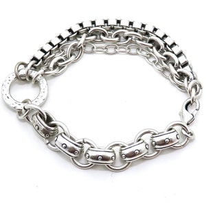 May include: Silver-toned bracelet featuring a variety of chain styles. The bracelet includes a hammered ring detail, a box chain, and a lobster clasp closure. The design incorporates multiple chain link styles for a layered look.