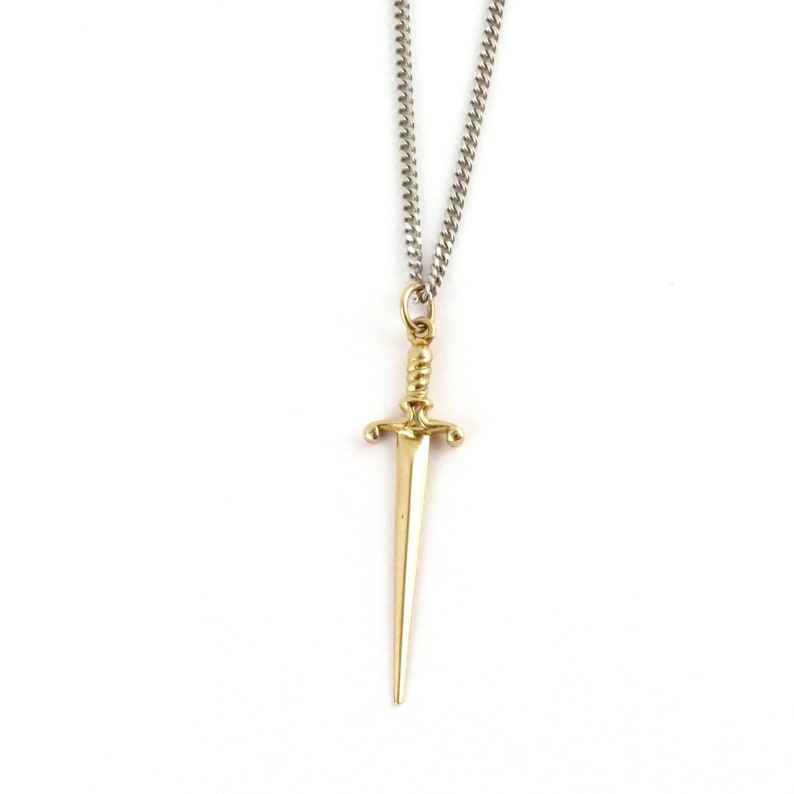 Peut inclure: Un collier avec un pendentif en forme de dague dor&eacute;e et une cha&icirc;ne en argent.