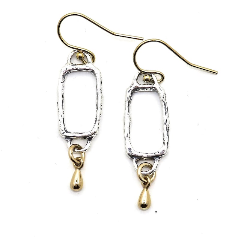 Op de afbeelding: Zilveren en gouden oorhangers met een rechthoekige vorm en een traanvormige hanger.